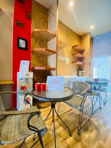 een kamer met tafels en stoelen en een rode muur bij Frutta Hostel in Patong Beach