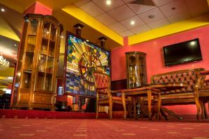 a dining room with a bench and a tv on a wall at Casino Motel Senator in Gevgelija