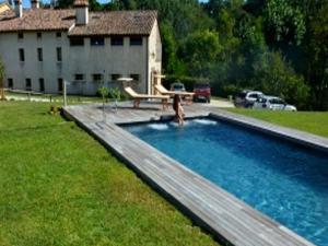 a woman is in a swimming pool with a picnic table at Modern Farmhouse in Pagnano Italy near Forest in Asolo