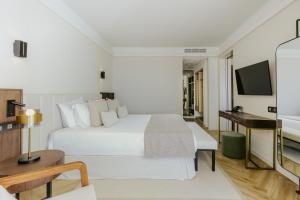 a hotel room with a large white bed and a desk at Golden Coast Beach Hotel in Protaras