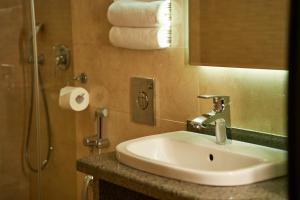 a bathroom with a sink and a shower with towels at City Stay Bishkek in Bishkek