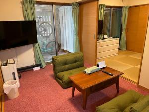 a living room with a couch and a coffee table at 日常を忘れる静かな空間の宿クレンリネスDanDan 