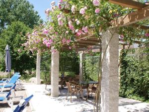 eine Pergola mit einem Tisch, Stühlen und rosa Blumen in der Unterkunft Spacious holiday home on estate near Covas in Covas