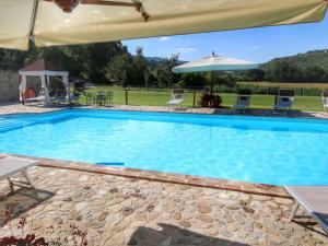 una grande piscina con ombrellone e sedie di Apartment on farm amidst the Umbrian hills a Todi