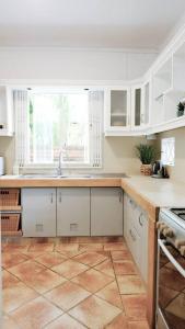 a kitchen with white cabinets and a tile floor at Tamarin River Villa in Tamarin