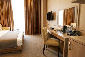 ein Hotelzimmer mit einem Schreibtisch und einem Bett in der Unterkunft City Stay Bishkek in Bischkek
