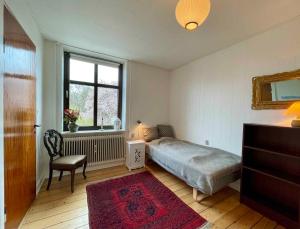 een slaapkamer met een bed, een stoel en een raam bij Charmerende Lejlighed I Stege Midtby in Stege