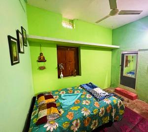 Dormitorio verde con cama con edredón colorido en Mani's place, en Hampi