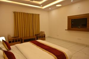 um quarto com uma cama e uma televisão de ecrã plano em Shiva Palace by Golden Leaf Hotels em Haldwani
