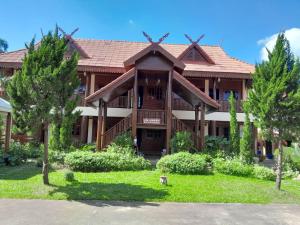 een groot houten huis met een gambrel dak bij Ben Guesthouse in Chiang Rai