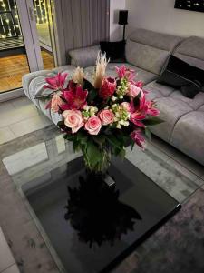 a vase of flowers on a glass table in a living room at Luxus Wohnung Köln/Phantasialand/Bonn/ Messe in Wesseling