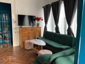 VulunVili Homestay في Tây Ninh: غرفة معيشة مع أريكة خضراء وطاولة