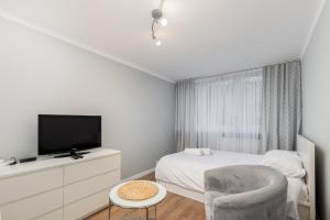 a bedroom with a bed and a tv and a chair at Weissa Comfort Studio in Krakow