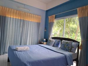 sypialnia z łóżkiem z niebieskimi ścianami i oknem w obiekcie Dr. House w mieście Khao Kho