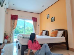 a woman sitting on the floor in a room with two beds at Dr. House in Khao Kho