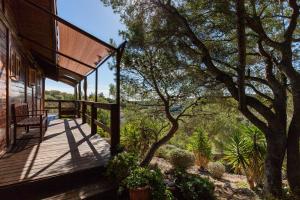 un porche de madera de una casa con un árbol en Wood House Massaranduba en Cubelles