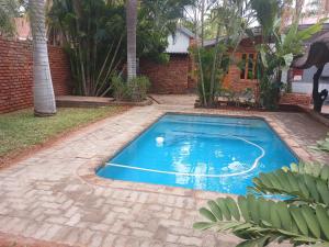 een zwembad in een tuin met een bakstenen muur bij Africa Dawn Guesthouse in Musina