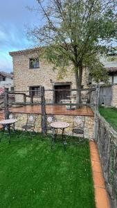 eine Terrasse mit zwei Tischen und einem Baum im Hof in der Unterkunft Casa Rural Negua en La Cuenca, Soria in La Cuenca