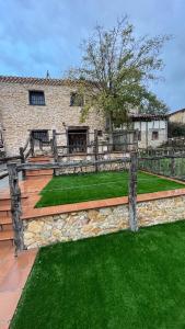 un mur de retenue en pierre avec une clôture et de l'herbe verte dans l'établissement Casa Rural Negua en La Cuenca, Soria, à La Cuenca