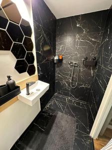 czarno-biała łazienka z umywalką i prysznicem w obiekcie The Lighthouse w mieście Pāvilosta