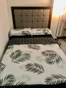 een bed met een zwart-witte sprei met palmbladeren bij JMC Homes in Manilla