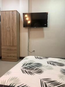 1 dormitorio con 1 cama y TV en la pared en JMC Homes, en Manila