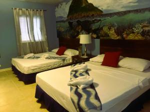 two beds in a hotel room with a painting on the wall at Malapascua Beach and Dive Resort in Logon