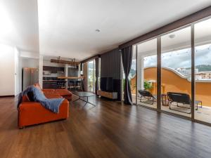 ein offenes Wohnzimmer mit einem orangenen Sofa und Stühlen in der Unterkunft Grand Penthouse by Grand Orlov Apart in Patong Beach