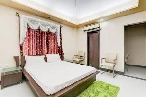 a bedroom with a bed and two chairs and a window at OYO Hotel M & c in Patna