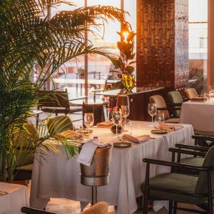 un restaurant avec des tables blanches, des chaises et des plantes dans l'établissement Swissotel Buyuk Efes Izmir, à Izmir