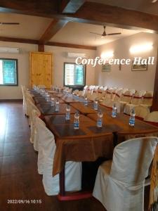 une salle de conférence avec de longues tables et des chaises blanches dans l'établissement Sundarban Tiger Roar Resort, à Purbbadulki