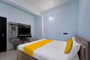 1 dormitorio con 1 cama con almohadas amarillas y TV en FabExpress JT Complex en Ranchi