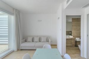 een witte woonkamer met een bank en een tafel bij Residence Capo Falcone Stintino in Stintino