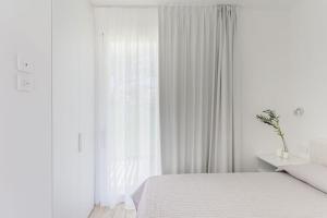 een witte slaapkamer met een bed en een raam bij Residence Capo Falcone Stintino in Stintino