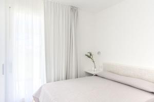 een witte slaapkamer met een bed en een raam bij Residence Capo Falcone Stintino in Stintino