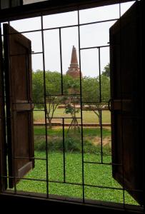 an open window with a view of a pagoda in the background at บ้านคุณยายอยุธยา in Phra Nakhon Si Ayutthaya