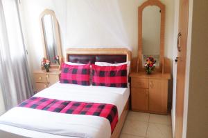 a bedroom with a bed with two red and black pillows at Nallur Mylooran Arangam in Jaffna