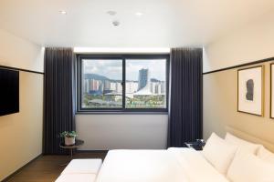 a bedroom with a white bed and a large window at Brown Dot Hotel Jinju in Jinju
