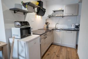 a small kitchen with white cabinets and a microwave at Apartmany ROSTER in Liptovský Mikuláš +26 photos