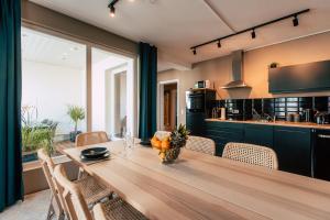 Luga Homes - Stadthaus في لايبزيغ: مطبخ مع طاولة وكراسي خشبية طويلة