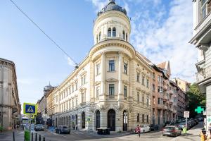 a large building with a tower on a street at Jupiter Home Buda in Budapest