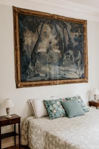 a painting hangs above a bed in a bedroom at La Chartreuse d'Ertan "Les maîtres" 4 étoiles in Saint-Christophe-des-Bardes