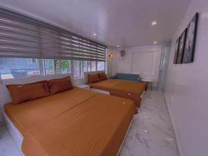 um quarto com duas camas e um sofá e uma janela em Cat Ba Santorini Homestay em Ilha de Cát Bà