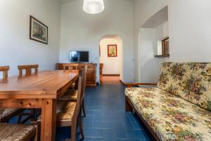a dining room with a wooden table and a couch at Orbetello Giannella Apartment in Giannella