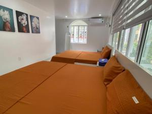 1 dormitorio con cama de color naranja y ventana en Cat Ba Santorini Homestay, en Cat Ba