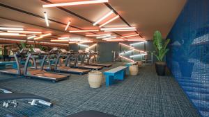 een fitnessruimte met rijen loopbanden en mensen op machines bij tent Mojito Suites in Magaluf