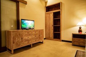 a living room with a television on a wooden entertainment center at Cozy Jungle View 1-Bedroom Villa with Private Pool in Ubud