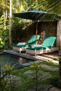two chairs and an umbrella next to a pool at Cozy Jungle View 1-Bedroom Villa with Private Pool in Ubud