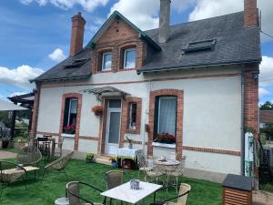 une maison avec des chaises et des tables devant elle dans l'établissement Les Garçonnières de Sologne, à Salbris