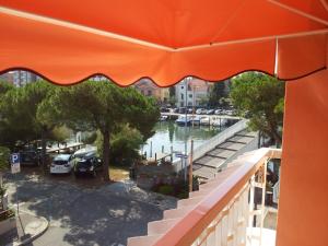 einen orangenen Regenschirm über einem Balkon mit Yachthafen in der Unterkunft Meublè Al Ponte in Grado